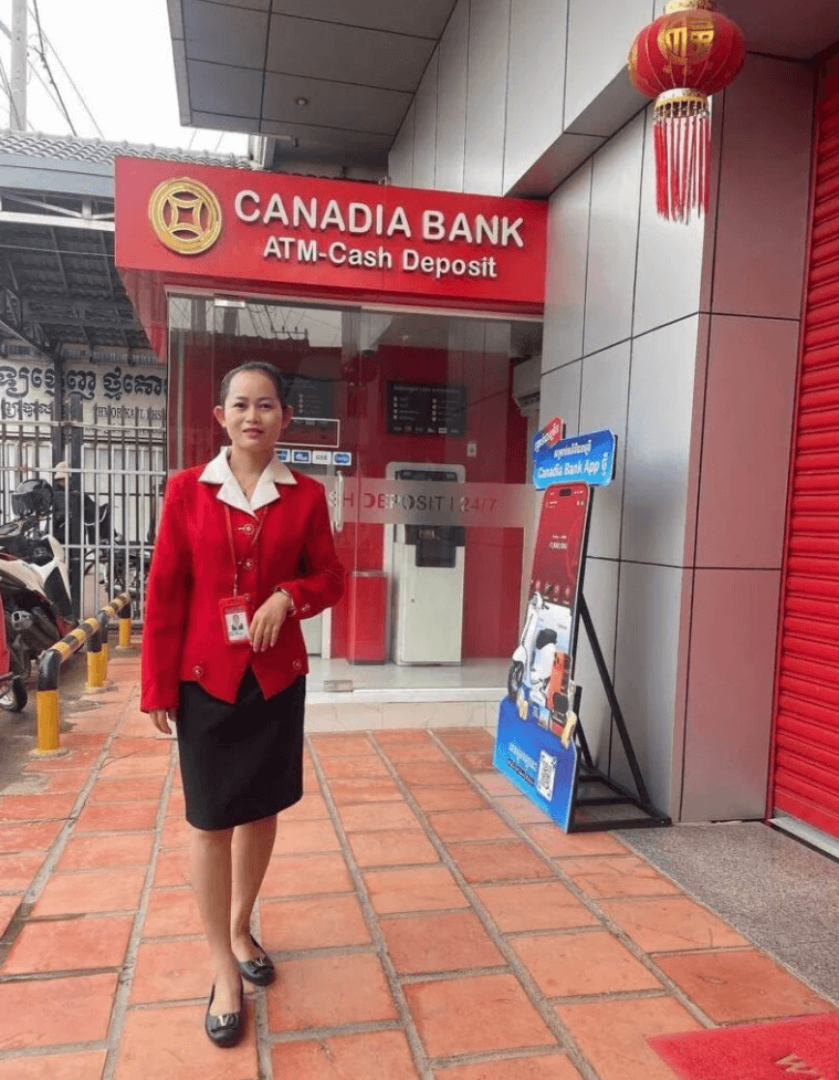 A professional woman standing outside Canadia Bank in a red uniform, representing the working mom behind the Sprout Upward blog.