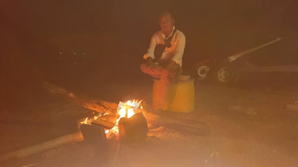 Author reflecting and writing an article by a campfire at night on Dream Garden